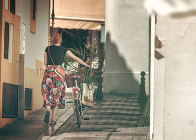 Rear view of woman walking by building