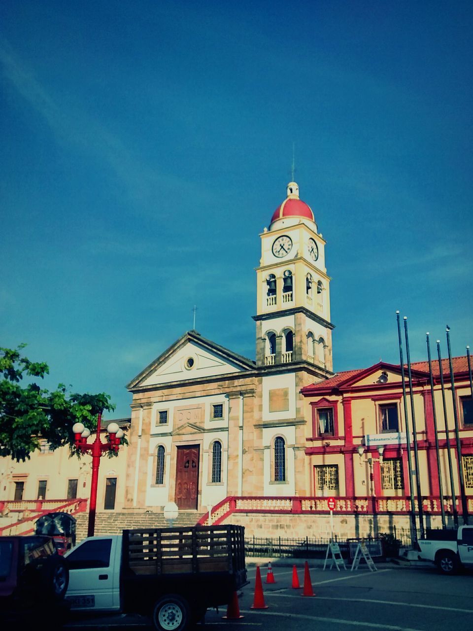 building exterior, architecture, built structure, church, religion, car, transportation, land vehicle, street, sky, mode of transport, low angle view, blue, place of worship, road, spirituality, city, clock tower