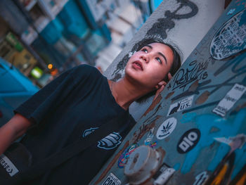 Woman looking away while standing by graffiti