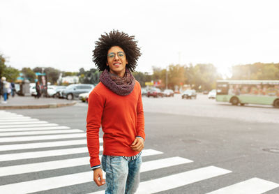 Portrait of smiling afro young man standing on zebra crossing in city