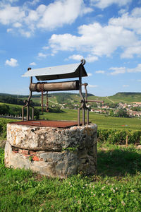 Empty bench on field against sky