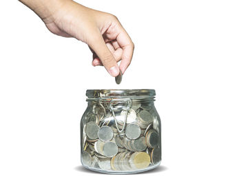 Close-up of hand holding glass jar against white background