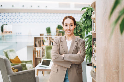 Adult smiling brunette business woman forty years in stylish beige suit and jeans at public place