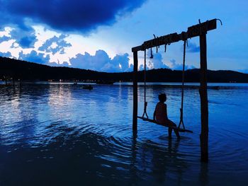 Silhouette man standing by lake against sky