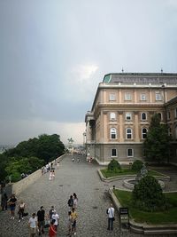 People by buildings in city against sky