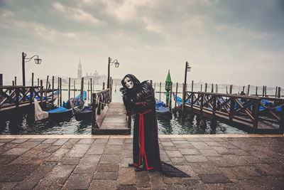 Man standing on pier against cloudy sky