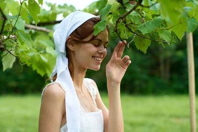 Portrait of young woman standing against plants