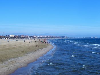 Group of people on beach against blue sky