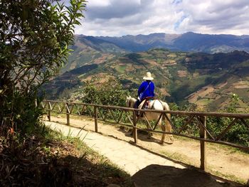 Person riding horse by wooden railing