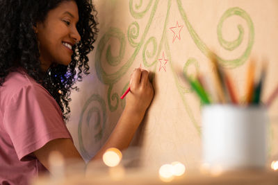 Smiling woman drawing on wall at home