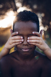 Close-up portrait of shirtless black child with white hands