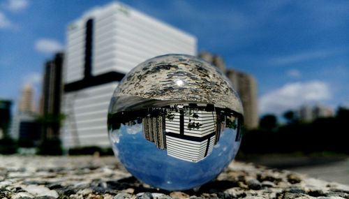 Buildings reflecting on crystal ball in city