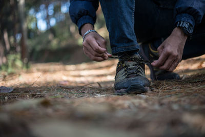 Low section of man tying shoe on field