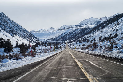 Road amidst snowcapped mountains against sky