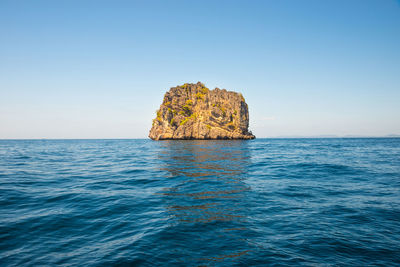 Scenic view of rock formation in sea against clear sky