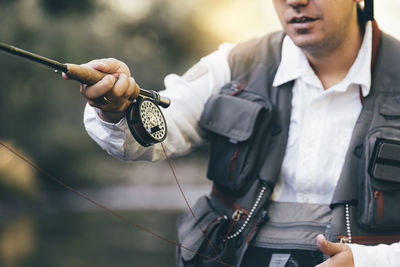 Midsection of man holding camera while standing outdoors