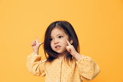 Portrait of young woman against yellow background