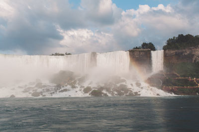 Scenic view of rainbow against waterfall