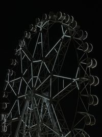 Low angle view of illuminated ferris wheel against black background