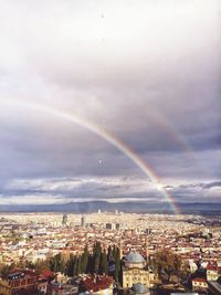 Rainbow over cityscape against sky