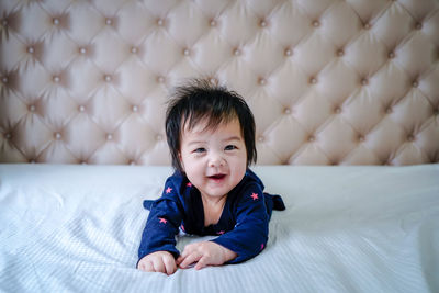 Cute little caucasian baby lying on bed at home. little cute girl in blue dress smiling to camera.