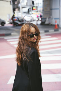 Woman wearing sunglasses standing on street in city