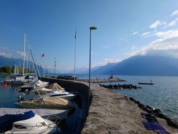 Sailboats moored in sea against sky