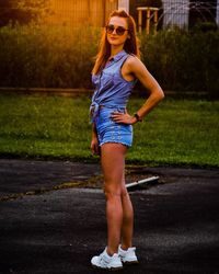 Full length portrait of young woman standing on road