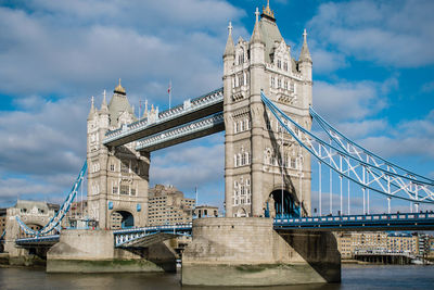 Low angle view of bridge over river against cloudy sky