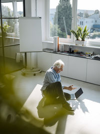 Businessman talking to video conference over laptop while sitting on floor at office