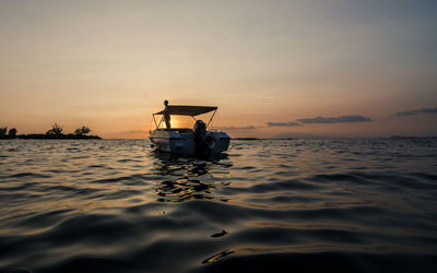 Silhouette boat in sea against sky during sunset