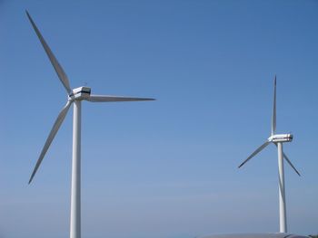 Low angle view of wind turbine against clear blue sky