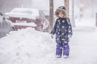 Portrait of smiling child standing on snowy sidewalk