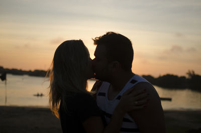 Couple kissing against sky during sunset