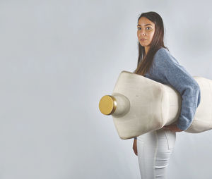 Portrait of young woman holding gift against white background