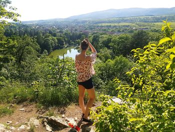 Young woman on tree by mountain against sky