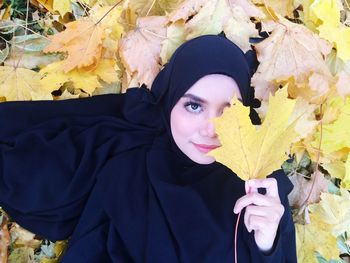 Close-up portrait of beautiful young woman with autumn leaves