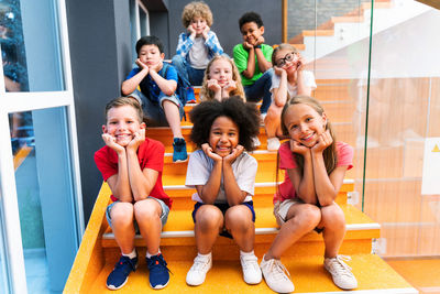 Portrait of happy friends sitting on staircase