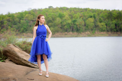 Full length of woman standing against blue water