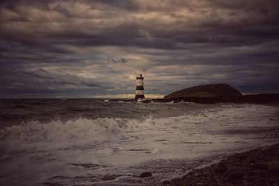 Lighthouse by sea against sky