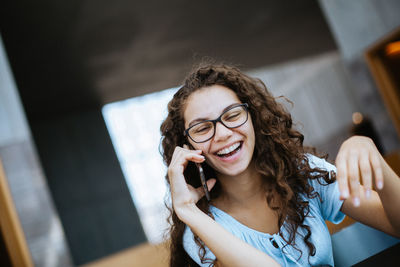 Smiling woman using mobile phone at table