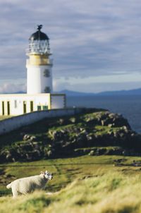 Lighthouse by sea against sky