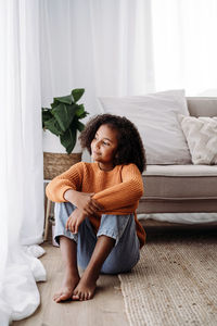 Thoughtful girl sitting in living room at home