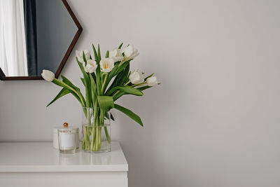 White tulips in a glass vase on a white chest of drawers.  spring home decor