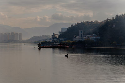 Scenic view of lake against sky in city