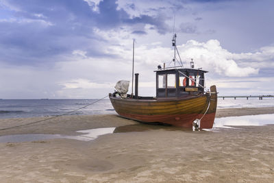 Boat moored on beach against sky