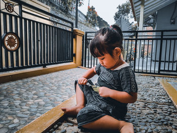 Full length of girl sitting on railing