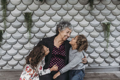 Portrait of sweet grandmother sitting close with twin grandchildren