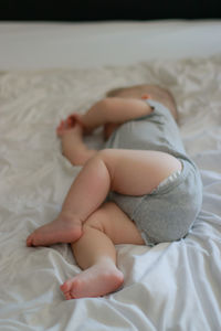 Low section of baby sleeping on bed at home