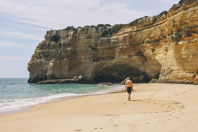 Rear view full length of shirtless man at beach